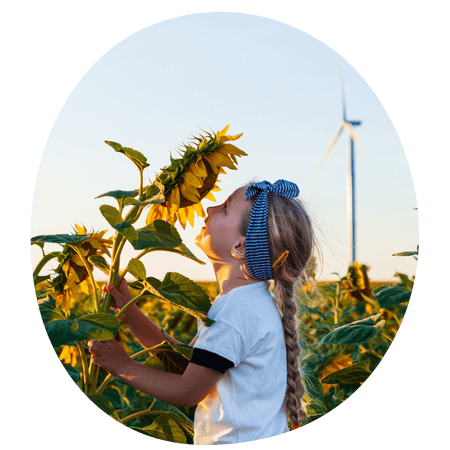 Girl in a sunflower field with a wind turbine in the background